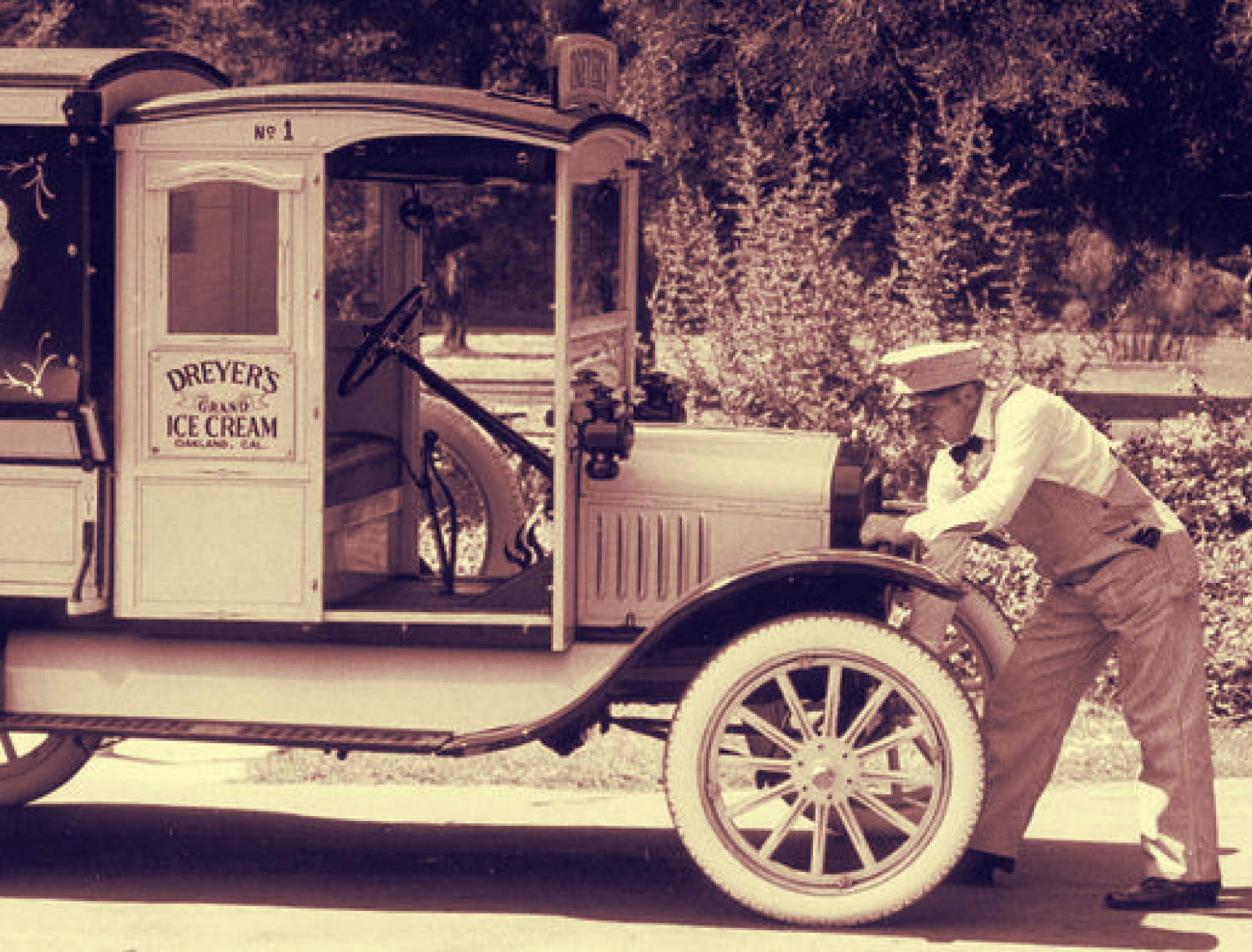 Black & white photo of the Dreyer's ice cream truck with ice cream man hand cranking the engine