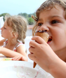 2 kids eating ice cream cones outside