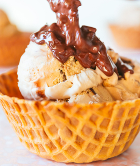 Dreyer's magic shell topping drizzled on waffle cone bowl with ice cream