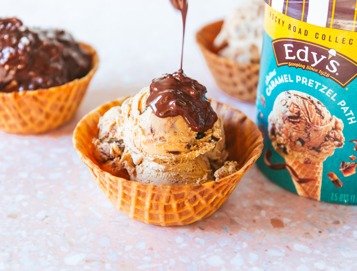 Edy's  salted caramel pretzel path ice cream in a waffle cone bowl with chocolate sauce