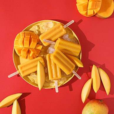 Outshine mango bars with fresh mangos on a plate