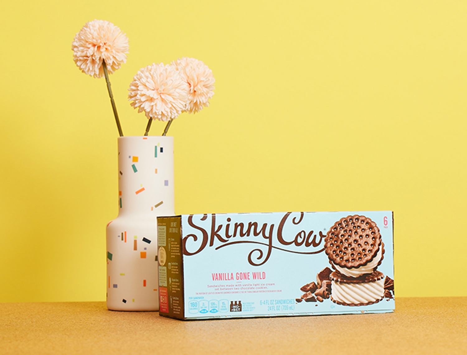 box of skinny cow vanilla gone wild ice cream bars on a yellow background with a vase and flowers